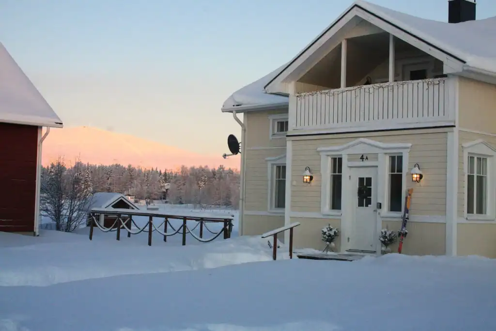 A cozy snow-covered house in Ylläsjärvi during winter sunset.