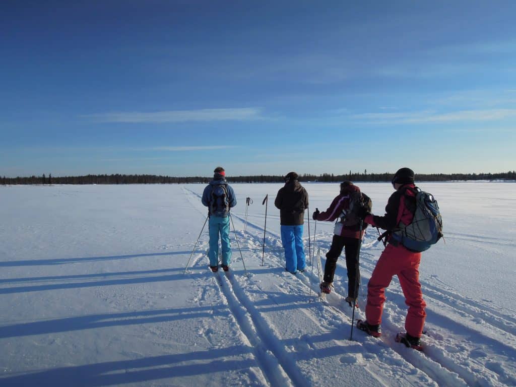 Group of four people snowshoeing across a snowy Arctic landscape in Ylläsjärvi.
