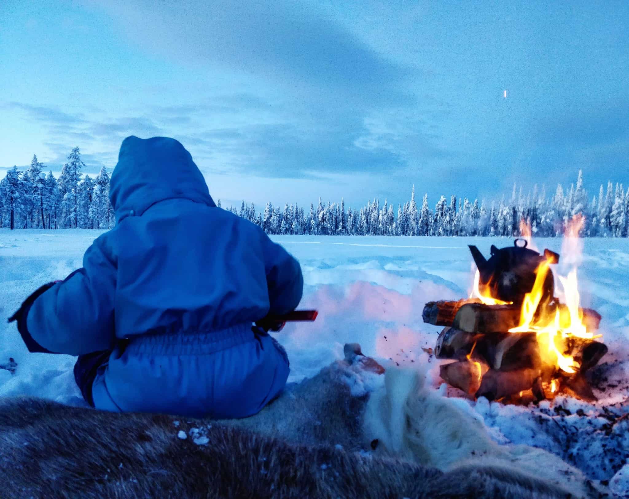 child ice fishing and open fire on frozen lake