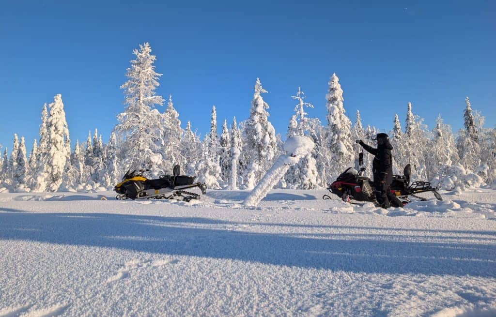 Snowmobile riders in snowy forest landscape in Ylläsjärvi, Finnish Lapland.