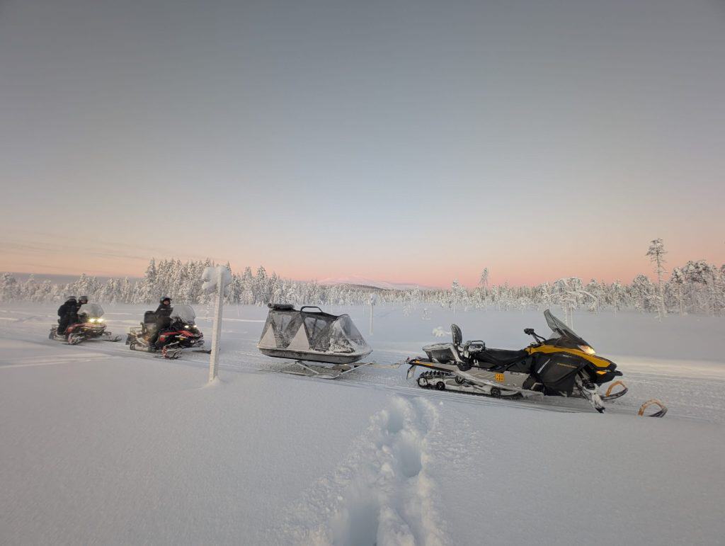 Snowmobile and snowshoeing adventure in snowy Lapland landscape.