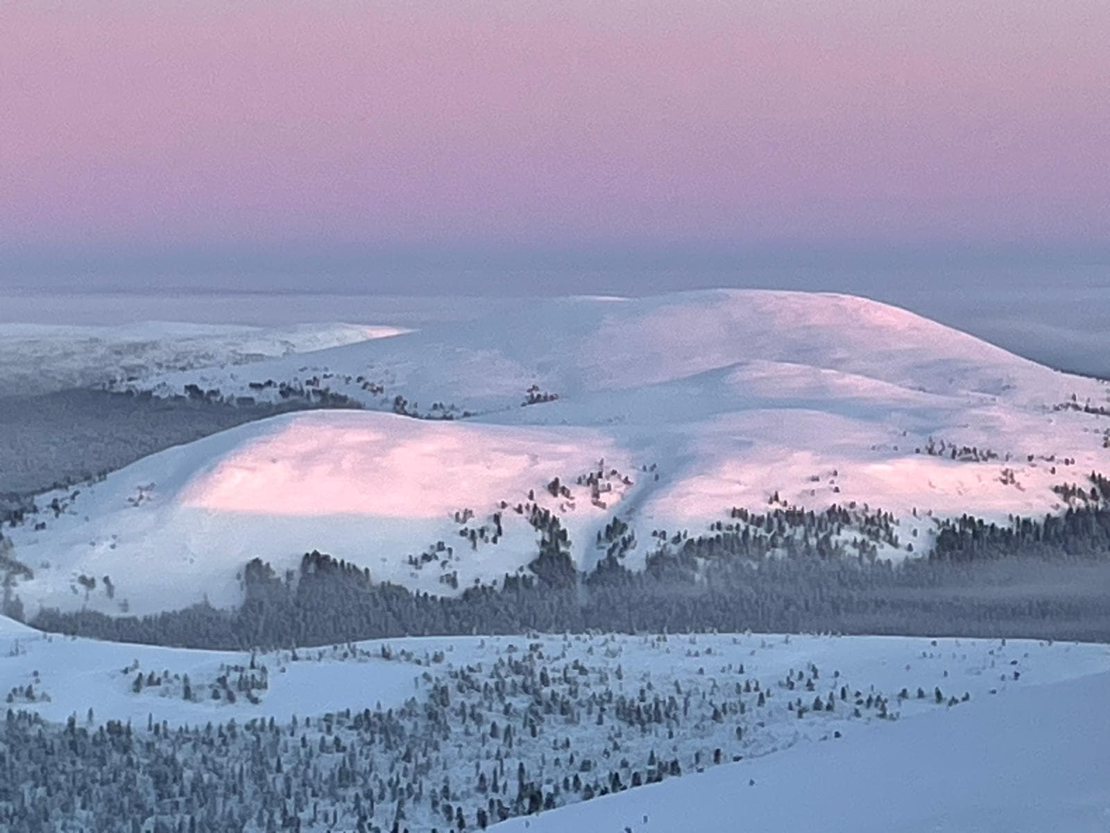 A snowy mountain landscape at dusk in Finnish Lapland.