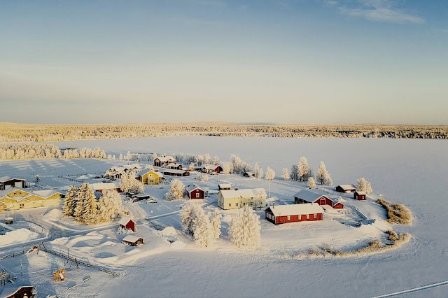 Snow-covered village in Finnish Lapland with colourful cabins and frosted trees.