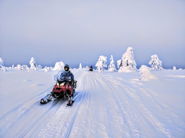 Snowmobile adventure in Ylläsjärvi, Finnish Lapland with snow-covered trees and open winter scener.