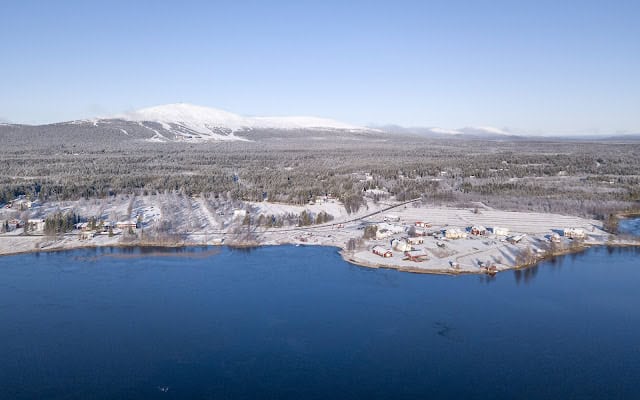 Scenic view of Ylläsjärvi Lake with snow-covered forests and distant mountain range in Finnish Lapla.