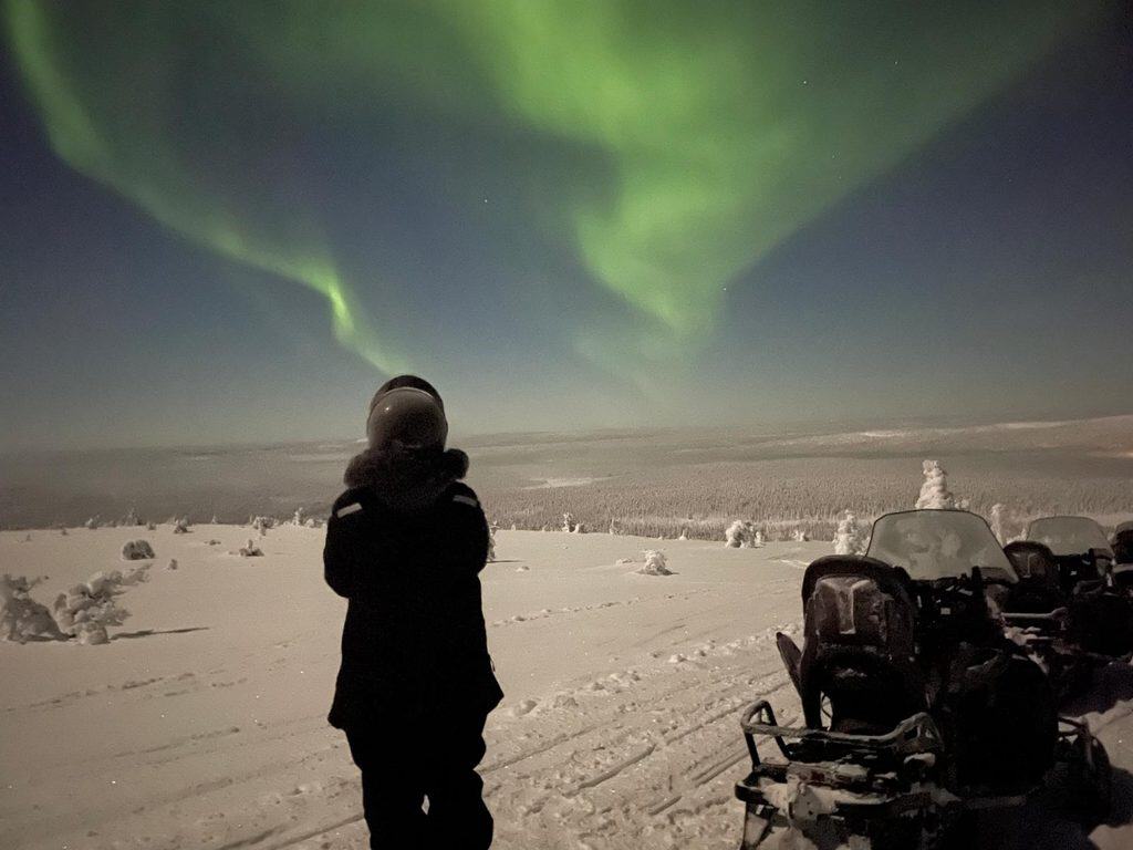 Person watching the Northern Lights in snowy Finnish Lapland.