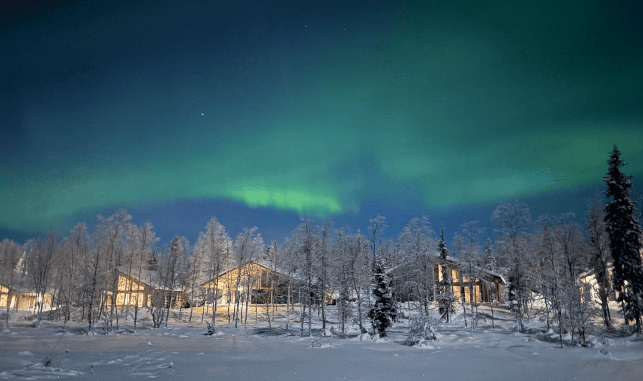 Aurora borealis over snowy cottages in Ylläs village, Finnish Lapland, at night